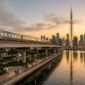 Futuristic Dubai Metro driverless train on elevated viaduct over Dubai Creek Harbour at golden hour