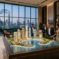 Investors reviewing illuminated 3D masterplan scale model in luxury Dubai sales gallery
