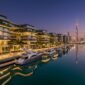 Ultra-luxury waterfront penthouses and superyachts along the Dubai Water Canal and Marasi Bay at dusk.